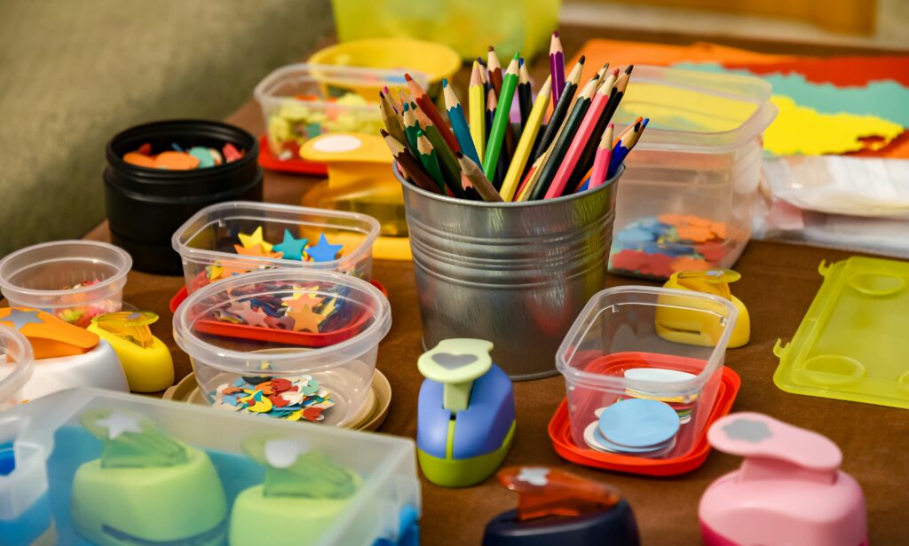 Image of craft materials on a table, such as colour pencils and shape punch tools